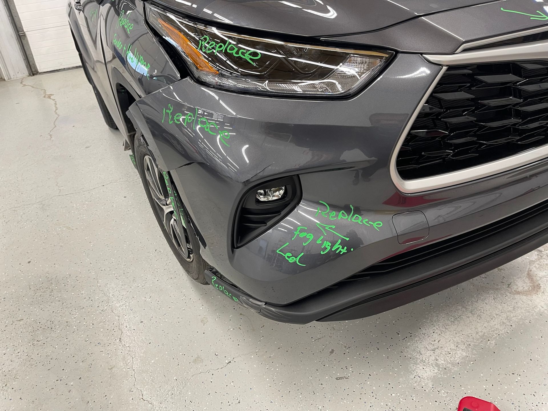 A gray toyota highlander is parked in a garage.
