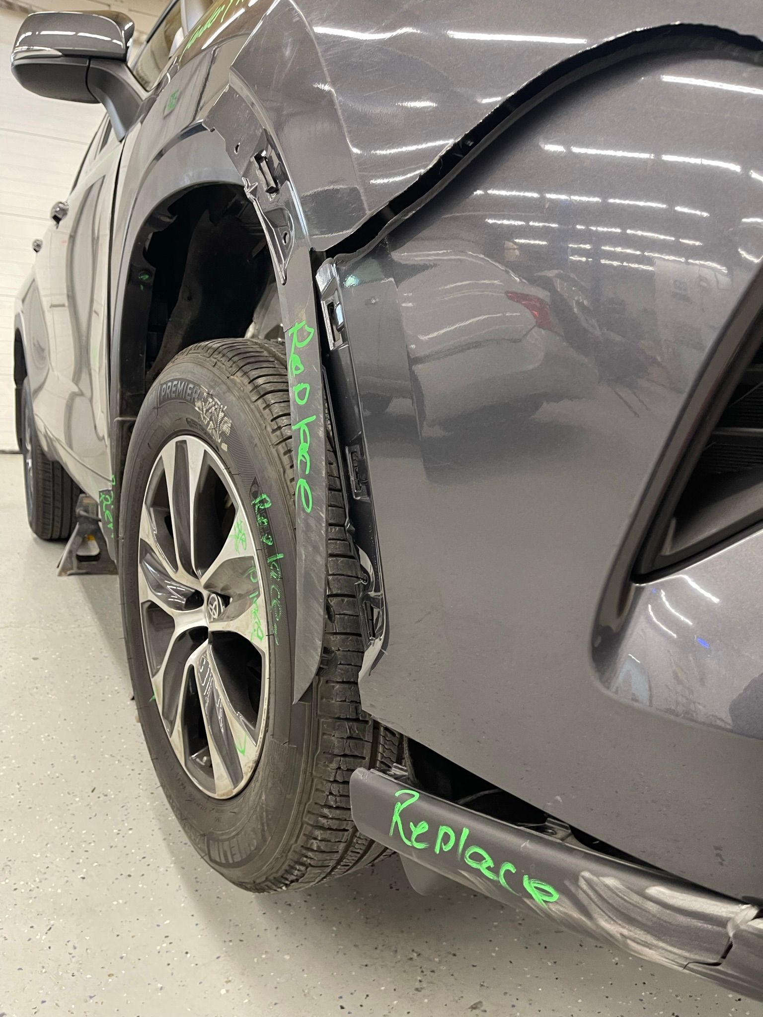 A car with a damaged fender is sitting in a garage.