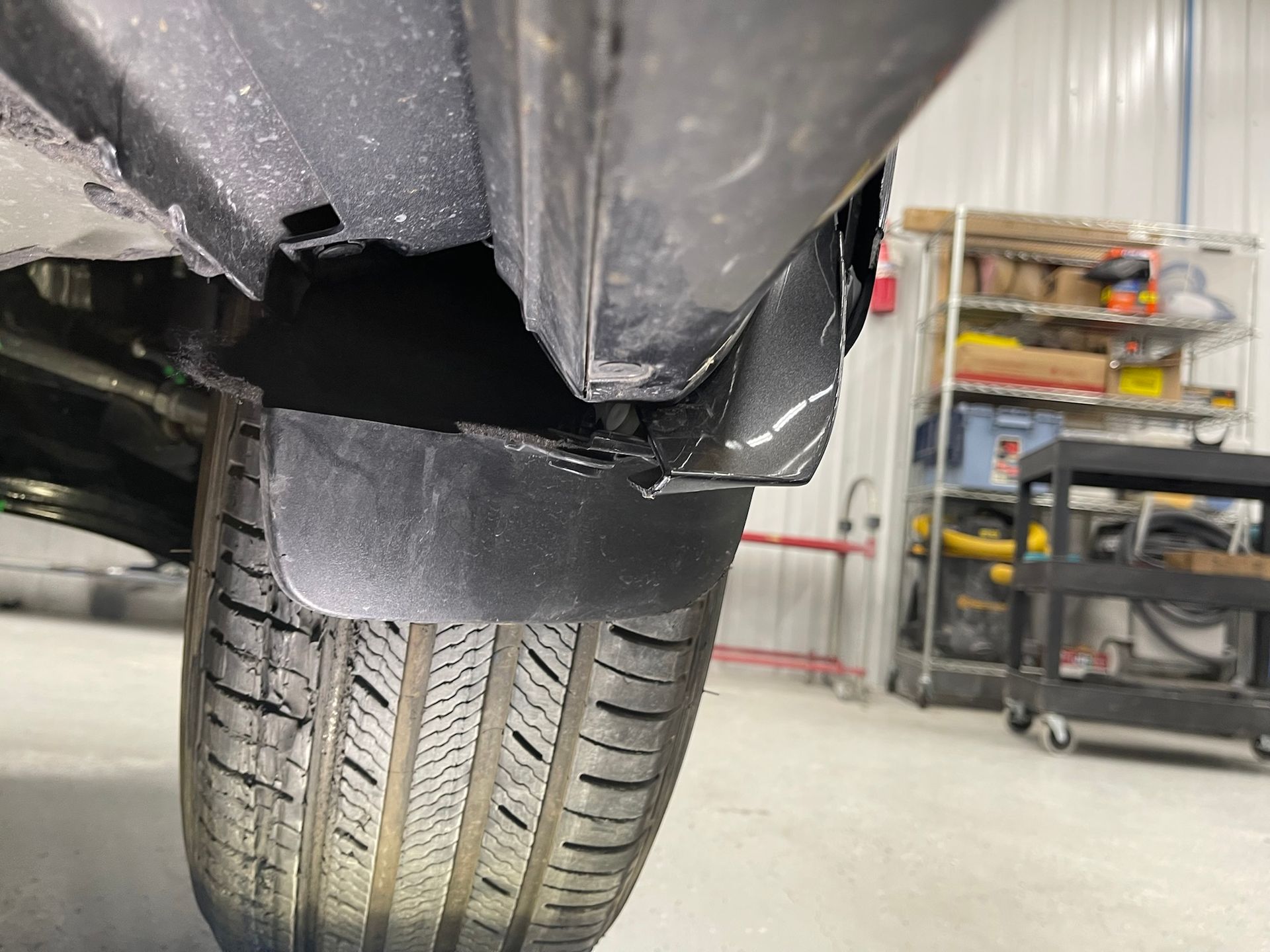 A close up of a car 's tire and fender in a garage.