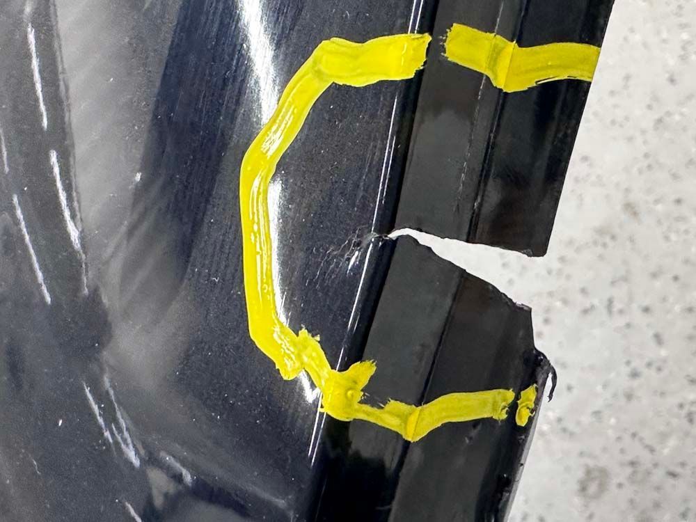 A close up of a broken bumper with yellow tape on it.