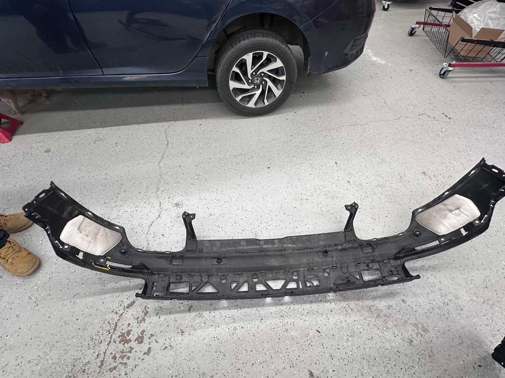 A blue car is parked in a garage next to a bumper.