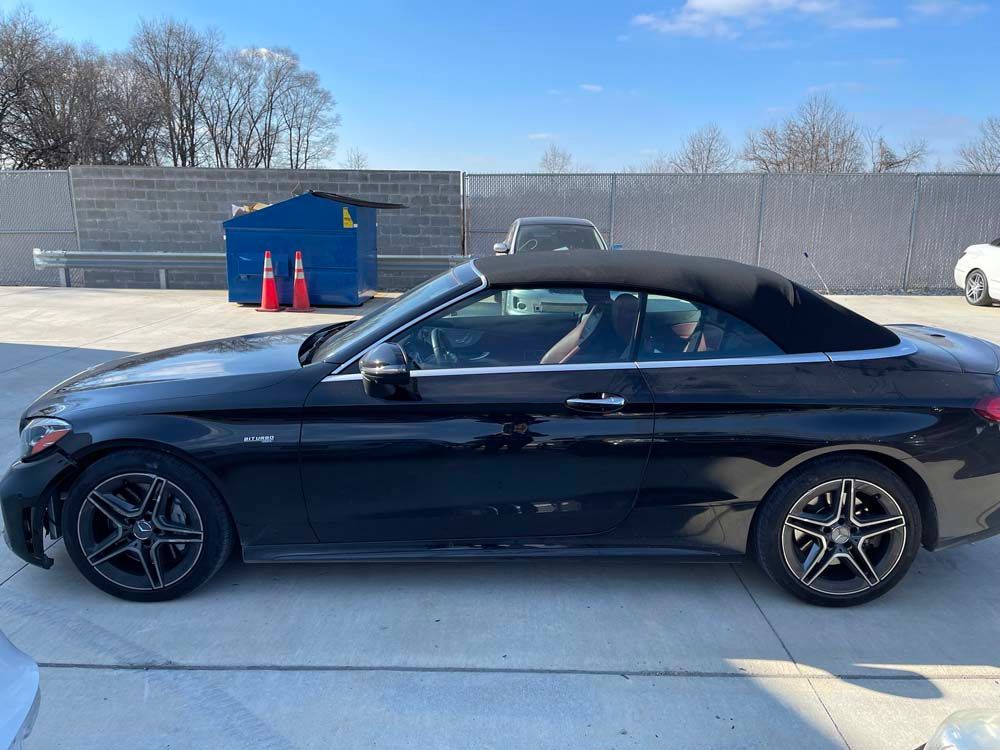 A black mercedes benz convertible is parked in a parking lot.