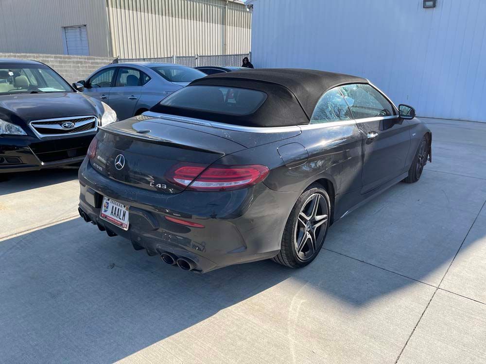 A black mercedes benz convertible is parked in a parking lot.