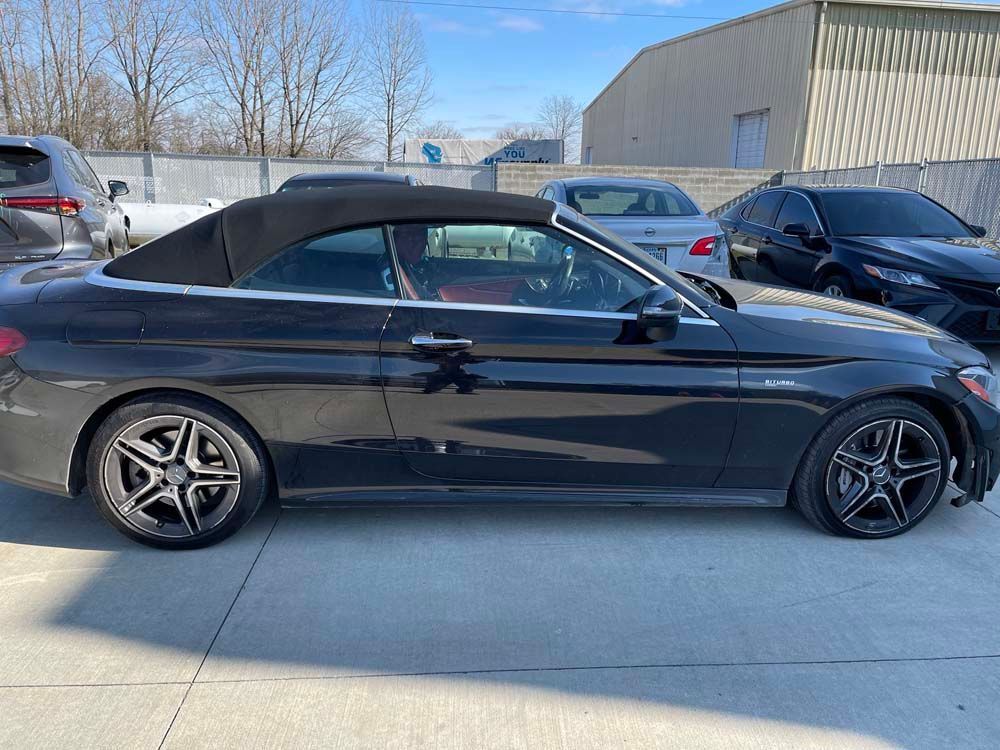 A black convertible car is parked in a parking lot.