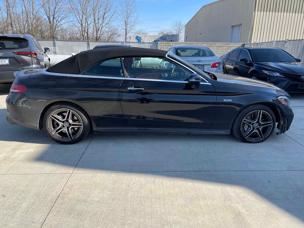 A black convertible is parked in a parking lot.