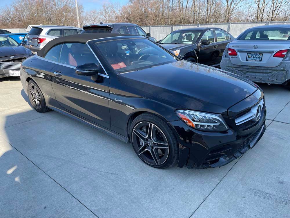 A black mercedes benz convertible is parked in a parking lot.