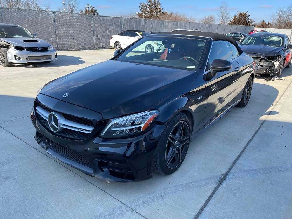 A black mercedes convertible is parked in a parking lot.