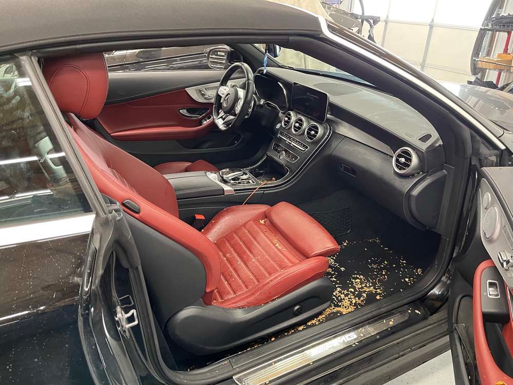 The interior of a black convertible car with red seats.