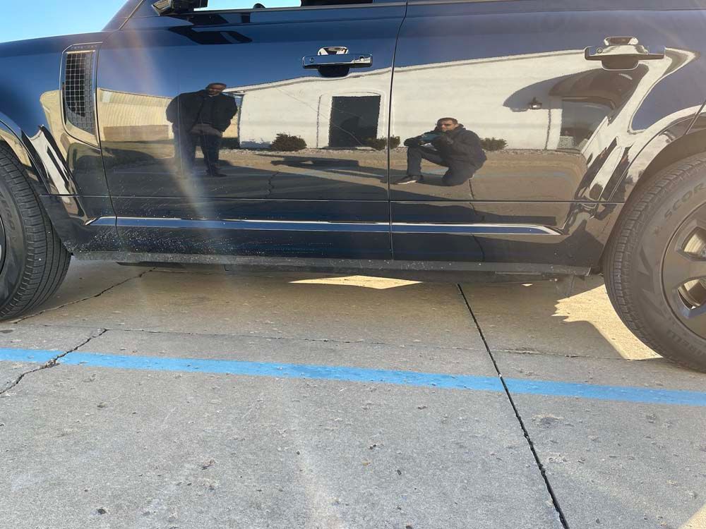 A black car is parked in a parking lot with a blue line.
