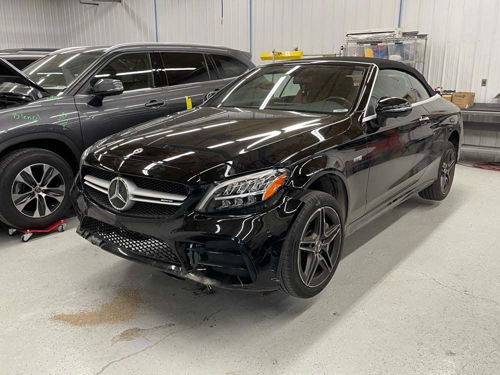 A black mercedes benz convertible is parked in a garage.