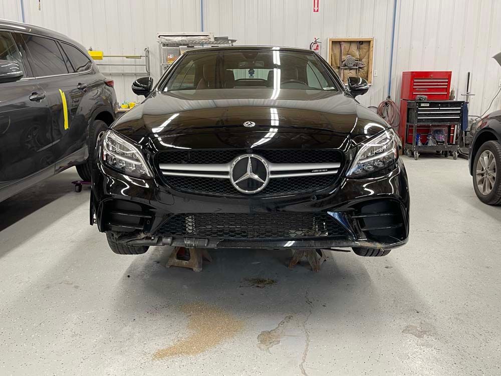 A black mercedes benz is parked in a garage.