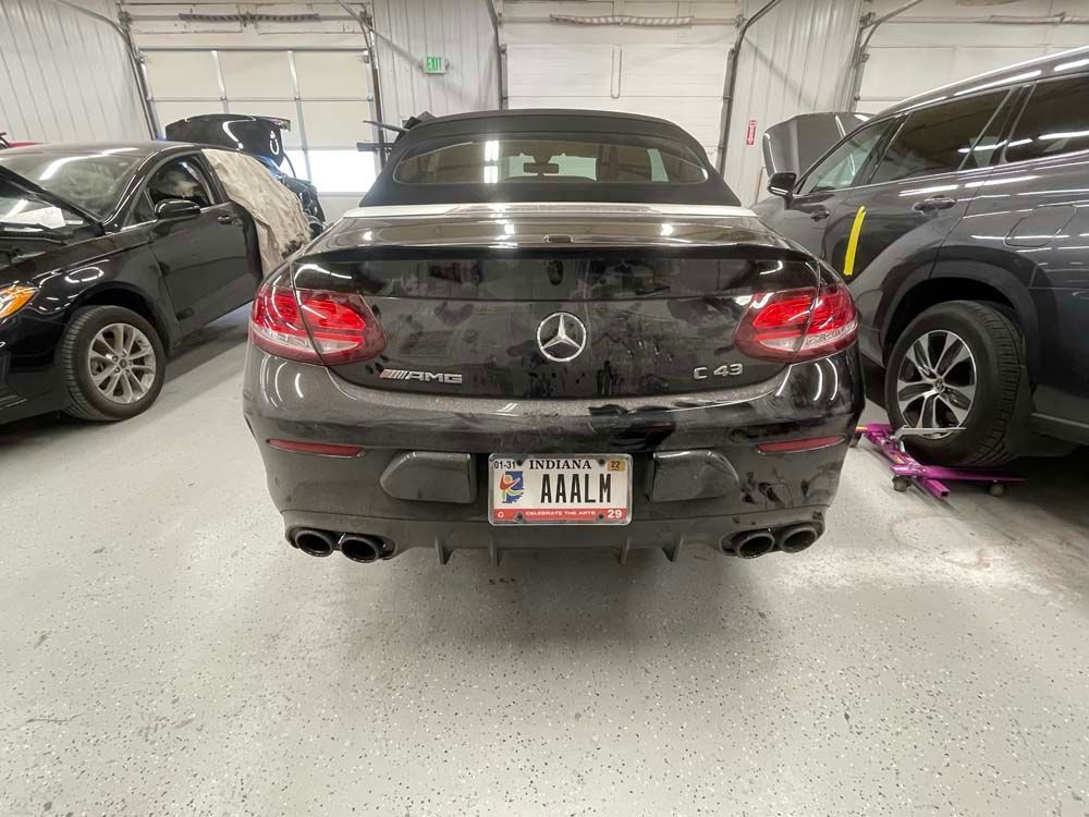 A black mercedes convertible is parked in a garage.