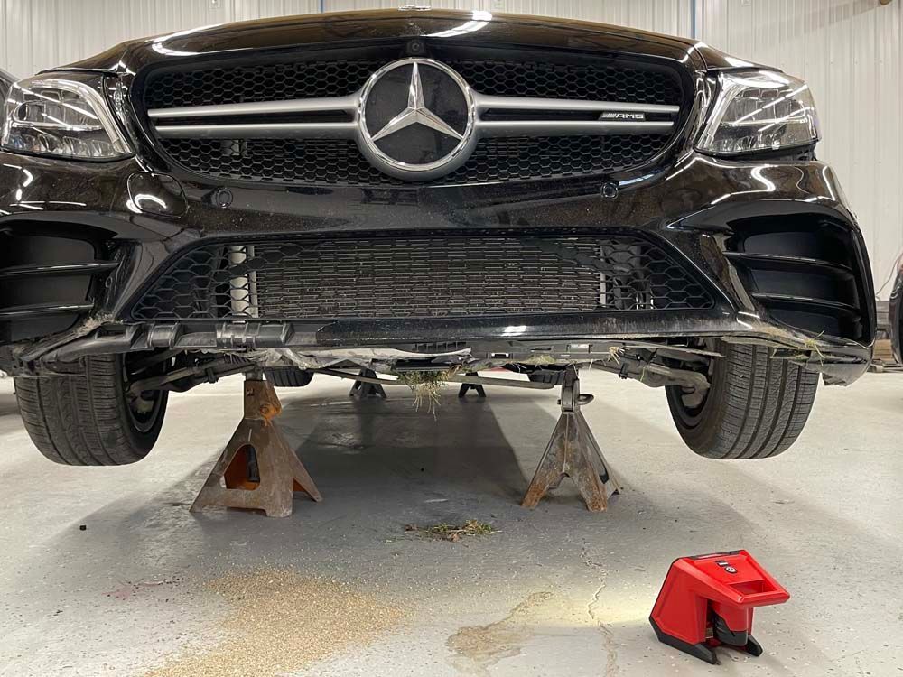 A black mercedes benz is sitting on wooden jack stands in a garage.