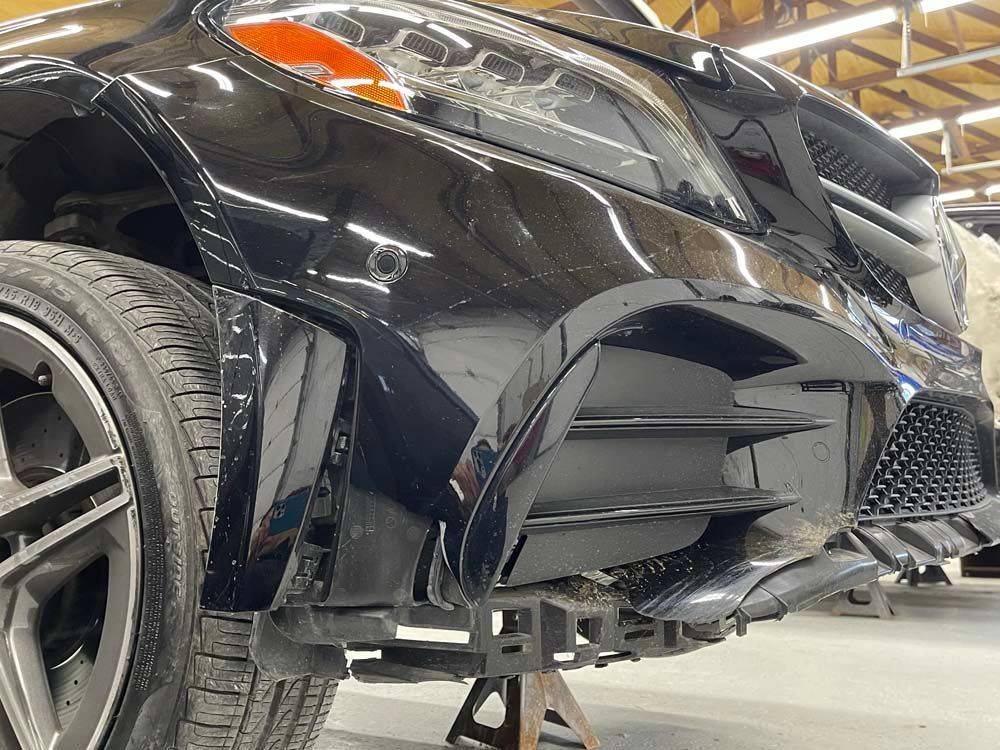 A black car is sitting on a jack in a garage.