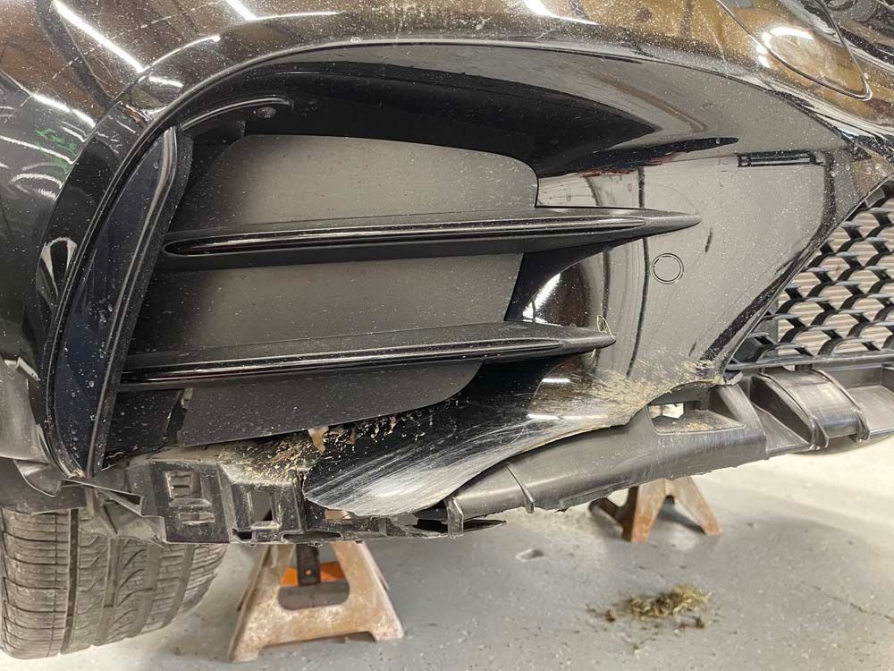 The front bumper of a black car is sitting on a wooden stand.