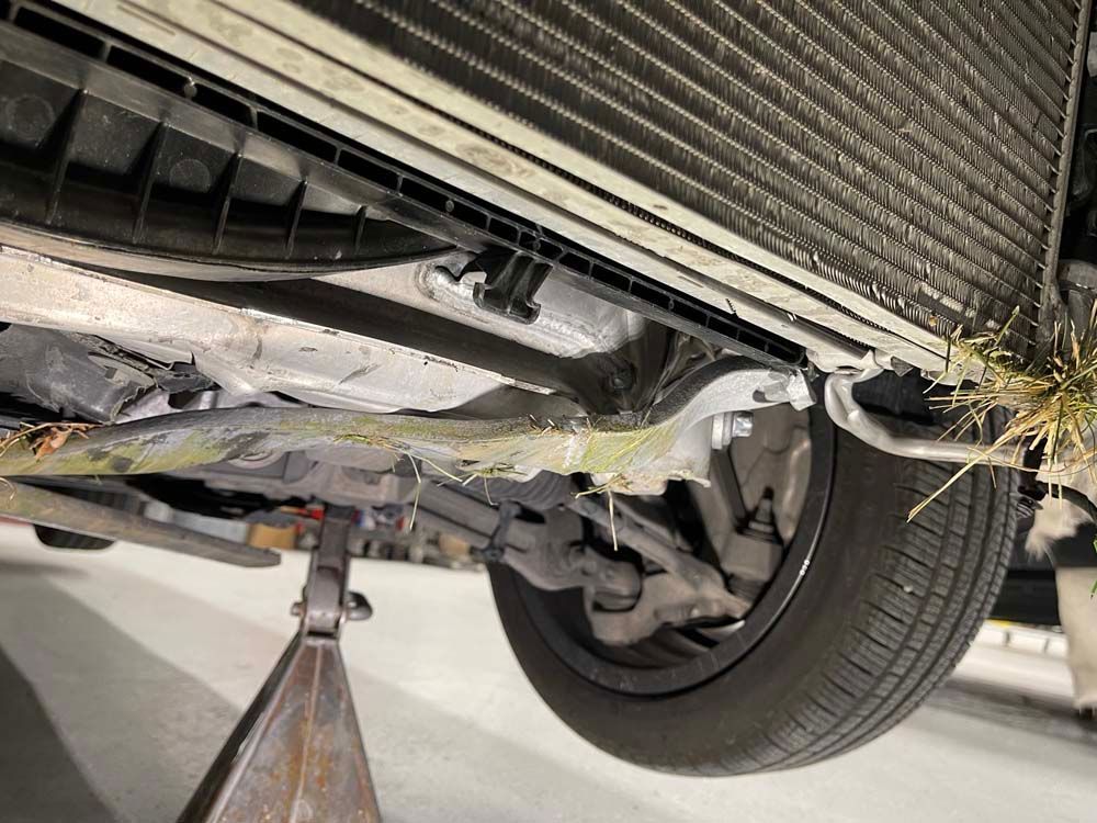 The underside of a car with a radiator and a tire on a jack.