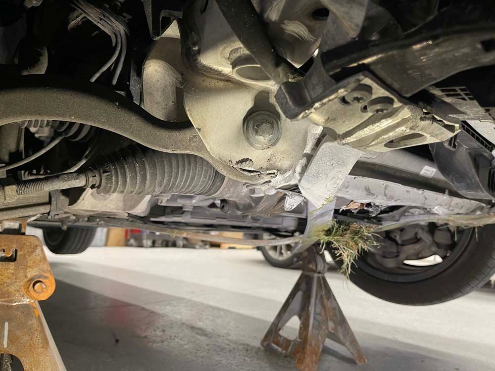 The underside of a car is sitting on a wooden jack.