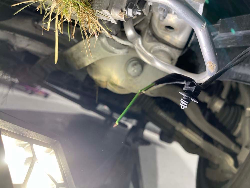 A close up of the underside of a car with grass growing out of it.