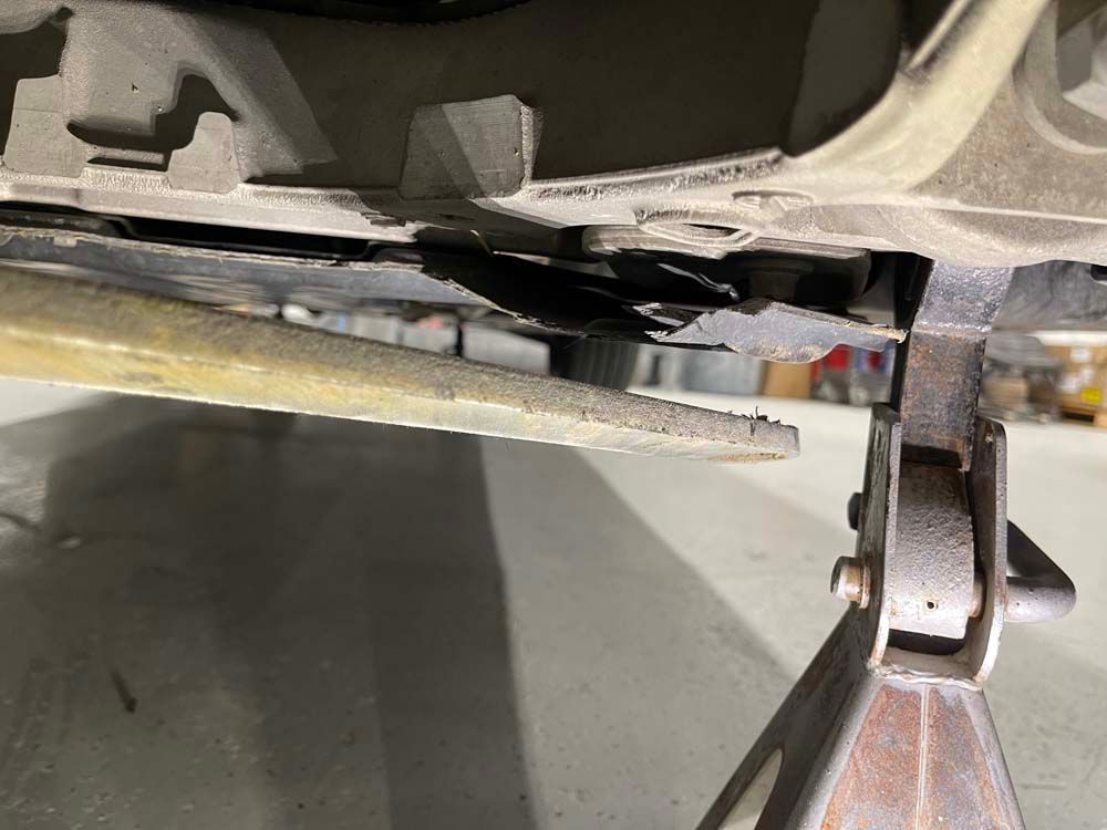 A car is sitting on a jack stand in a garage.