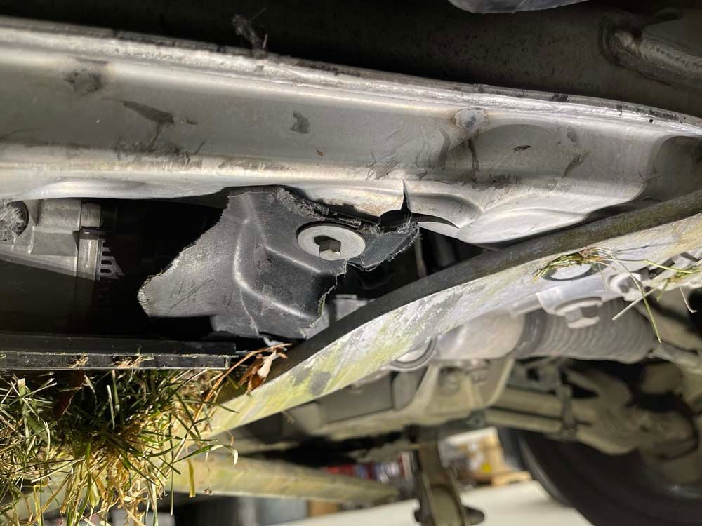 A close up of the underside of a car with grass growing out of it.