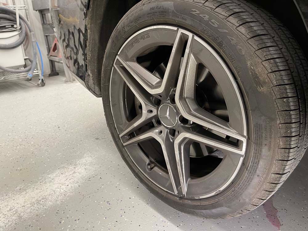 A close up of a car wheel and tire in a garage.