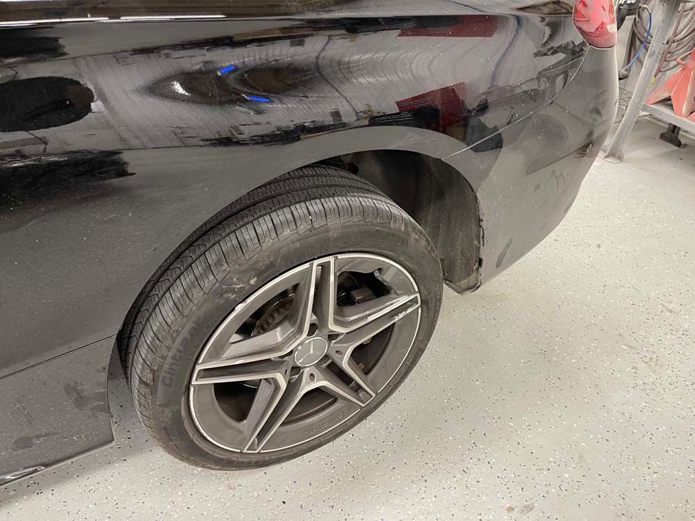 A close up of a black car 's wheel in a garage.