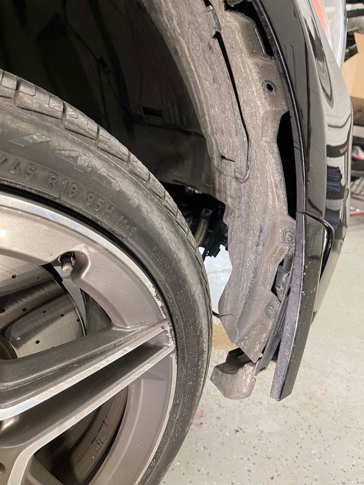 A close up of a car wheel and tire in a garage.