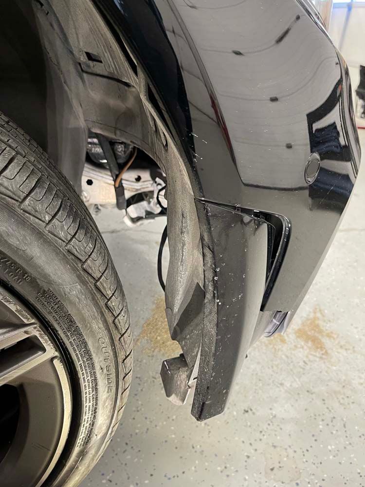 A close up of a car 's fender and tire in a garage.