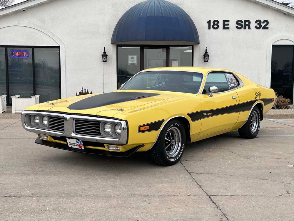 A yellow dodge charger is parked in front of a building.
