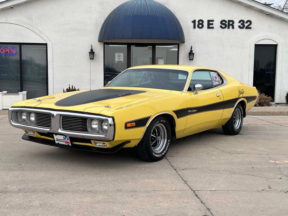 A yellow dodge charger is parked in front of a building.
