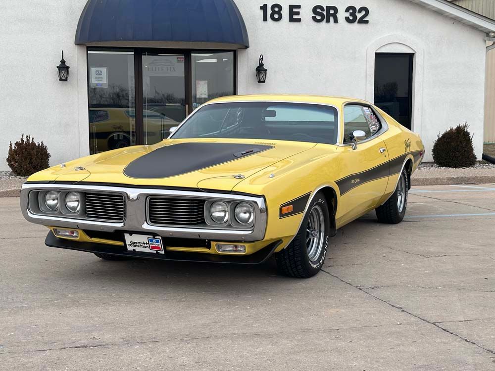 A yellow dodge charger is parked in front of a building.