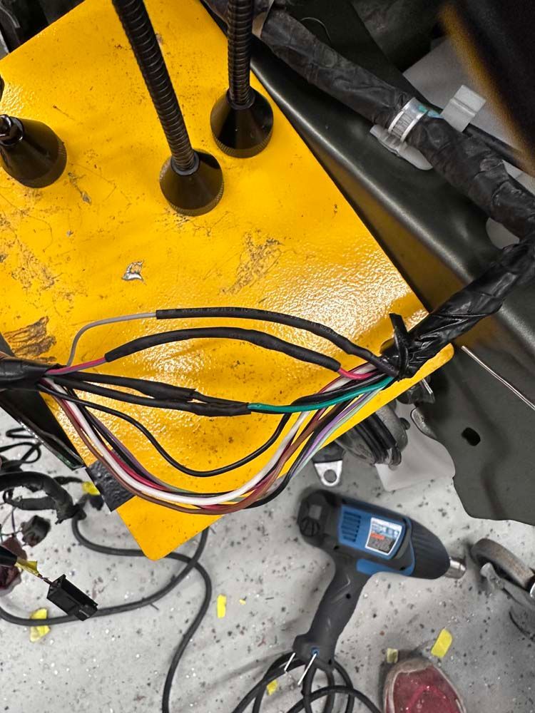 A bunch of wires are laying on the floor next to a drill.