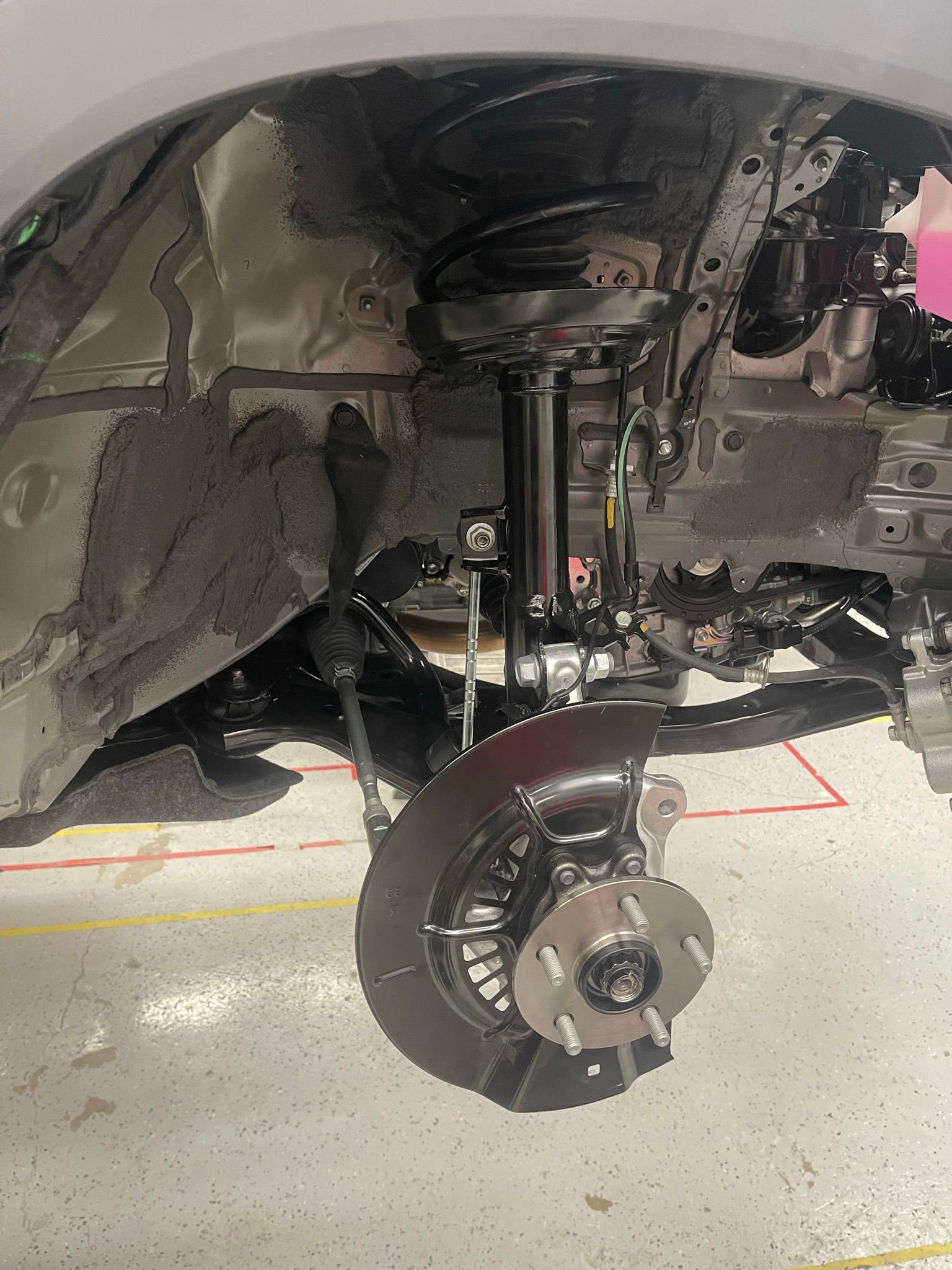 A close up of a car 's suspension and brake system in a garage.