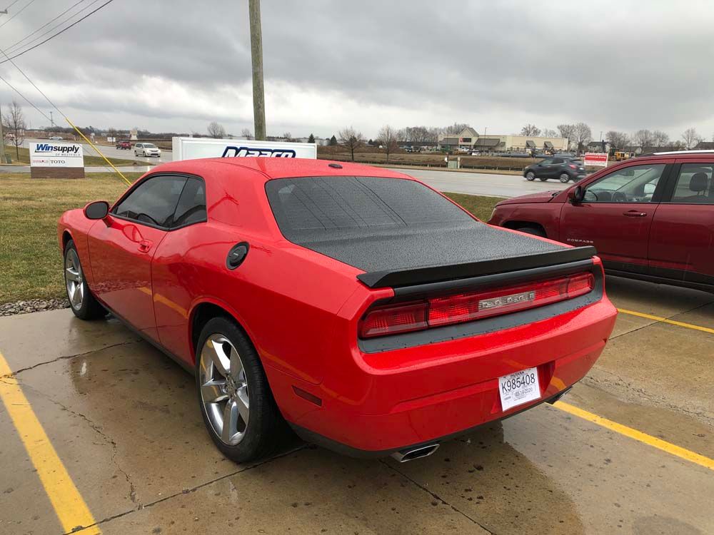 A red dodge challenger is parked in a parking lot.