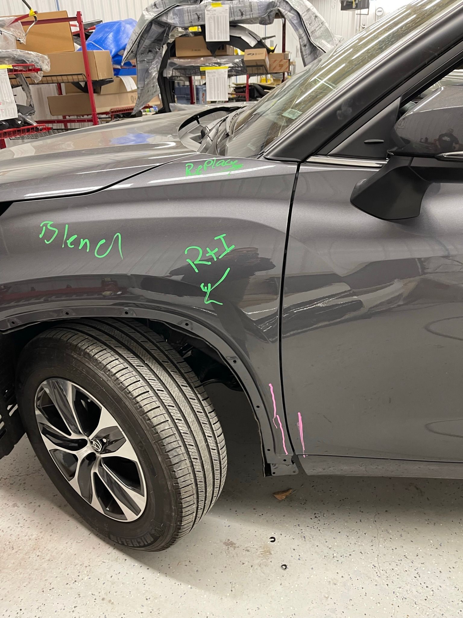 A gray car is sitting in a garage with a green marker on it.