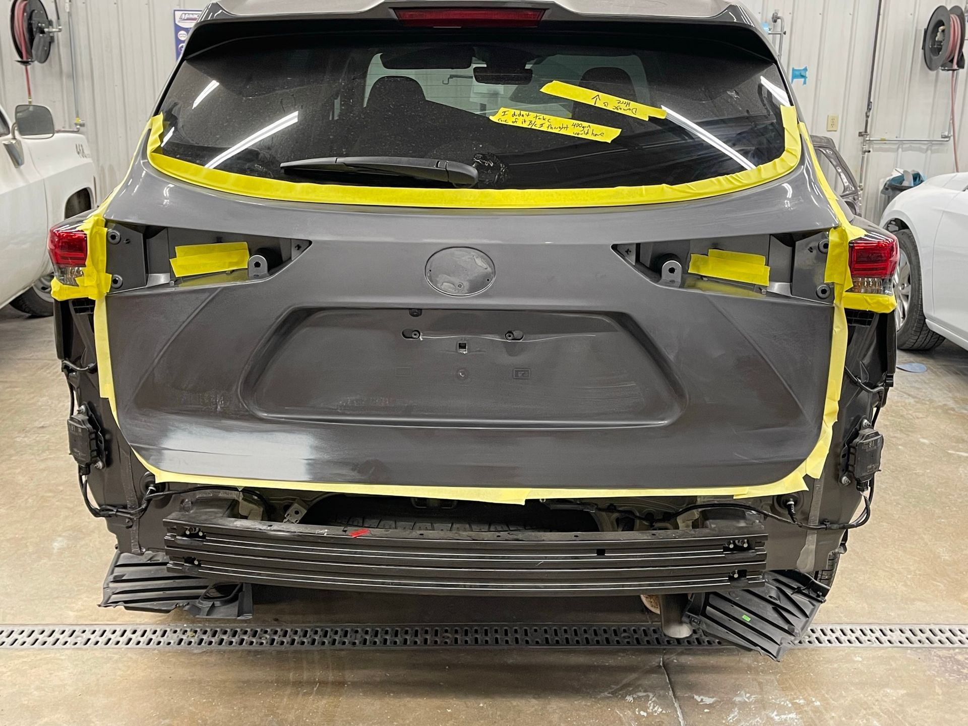The rear end of a car is being painted in a garage.