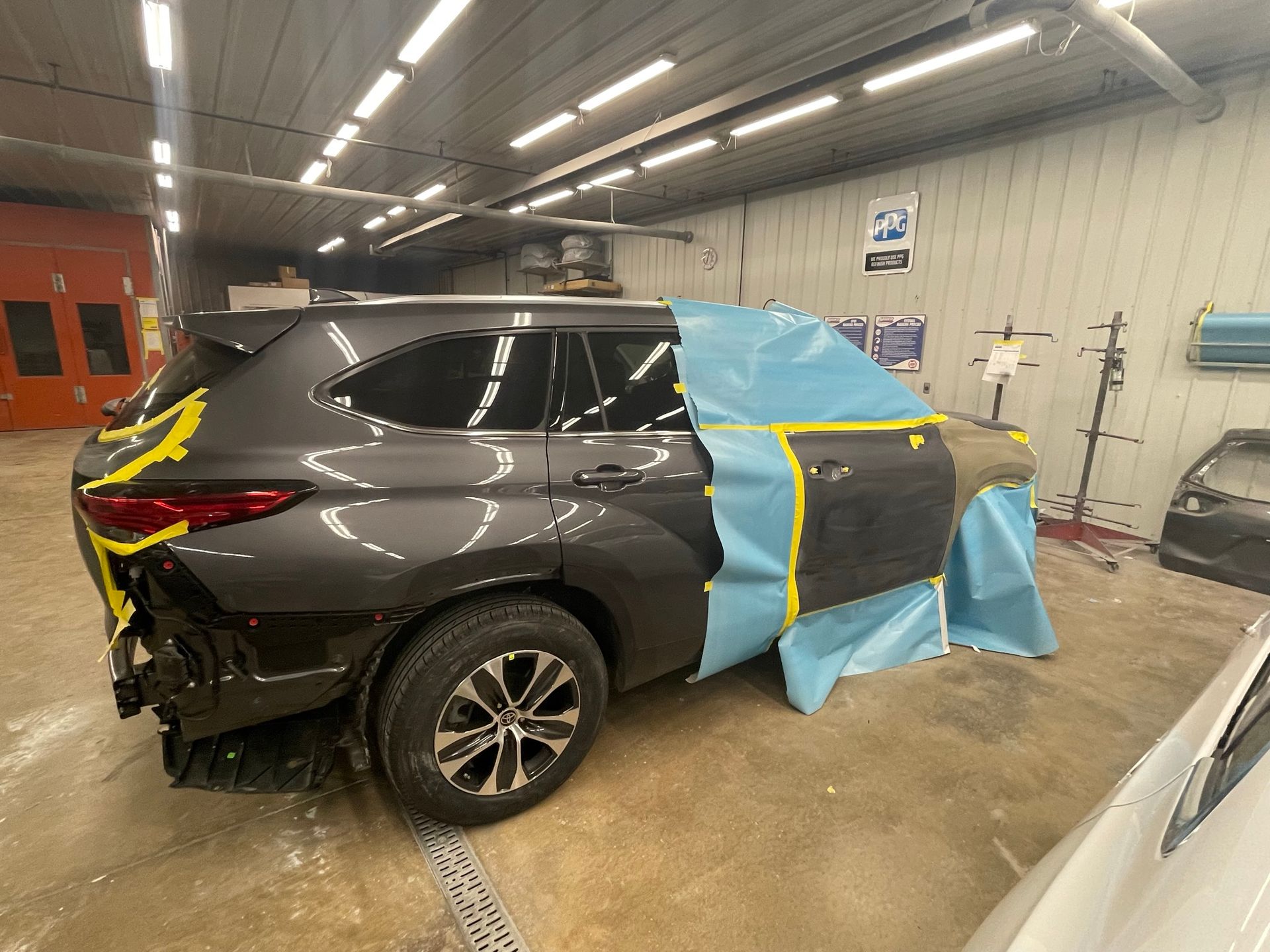 A car is sitting in a garage with a blue tarp on it.