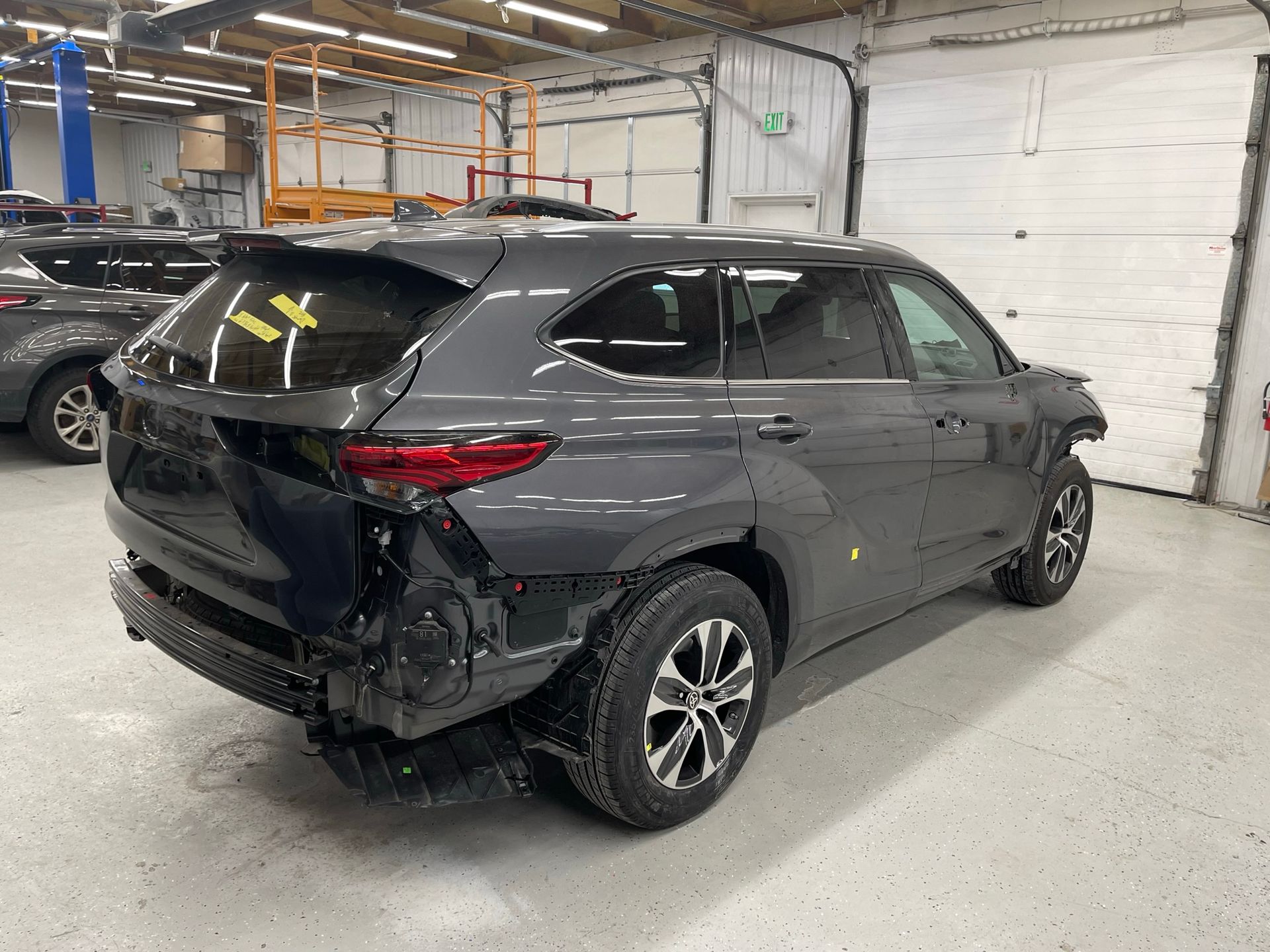 A damaged toyota highlander is parked in a garage.