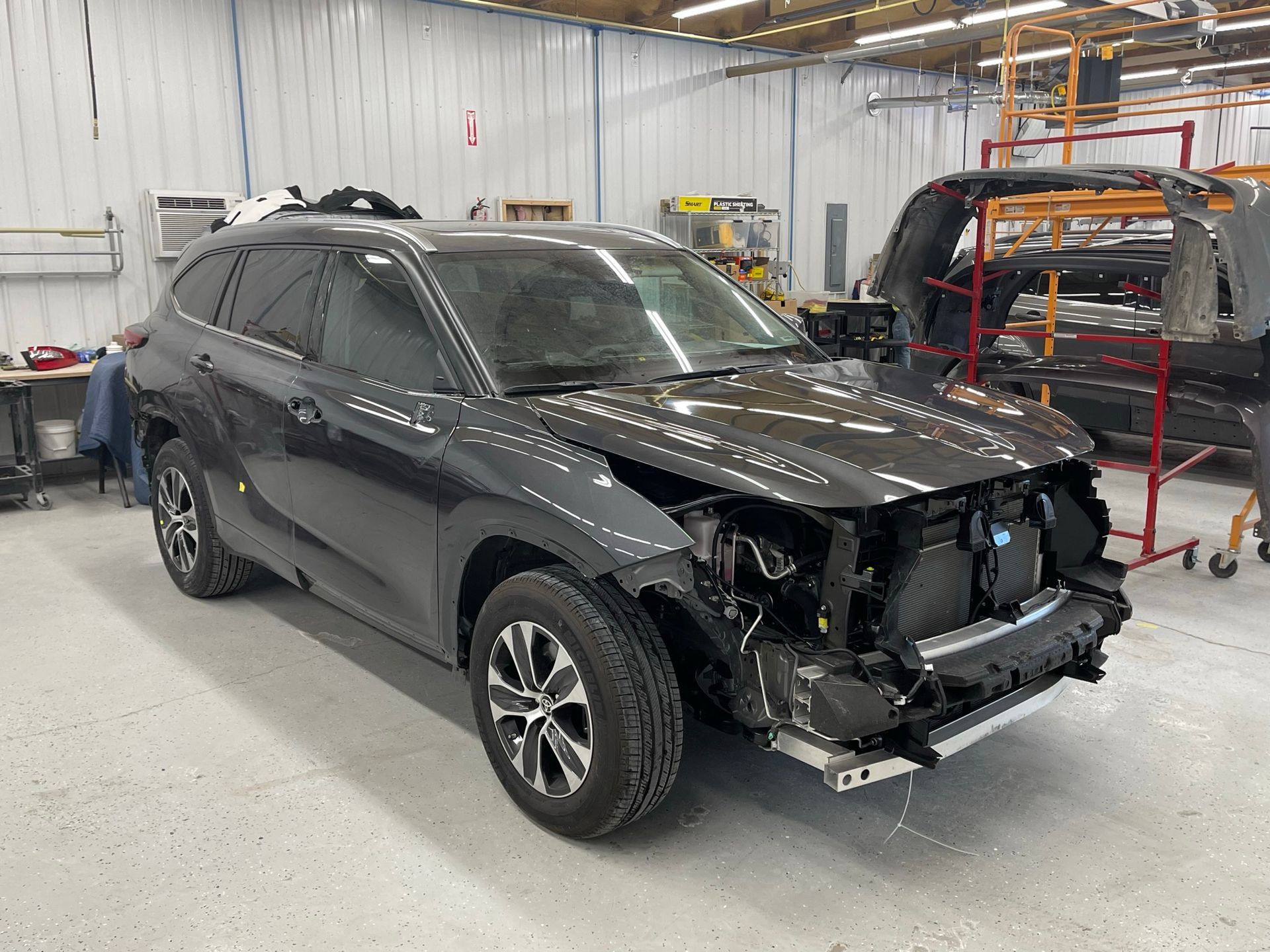 A black suv is sitting in a garage with its hood off.
