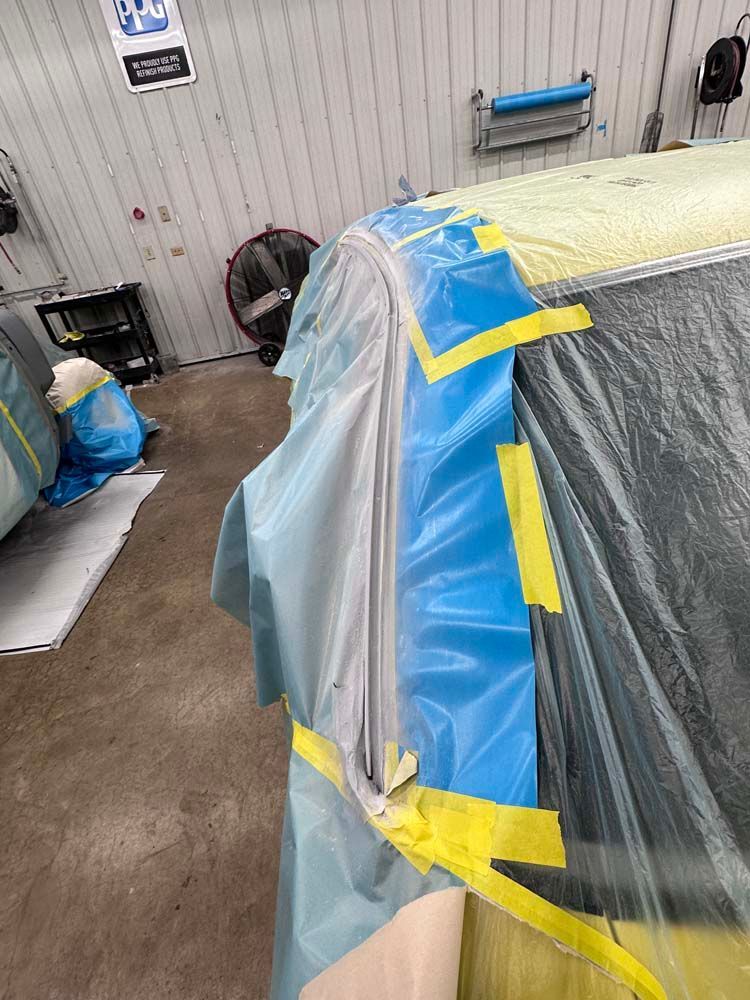A car is covered in plastic and tape in a garage.