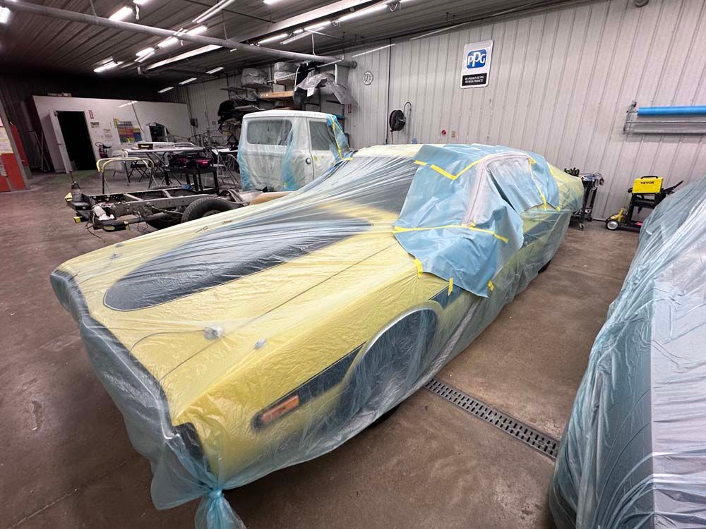 A yellow car is covered in plastic in a garage.