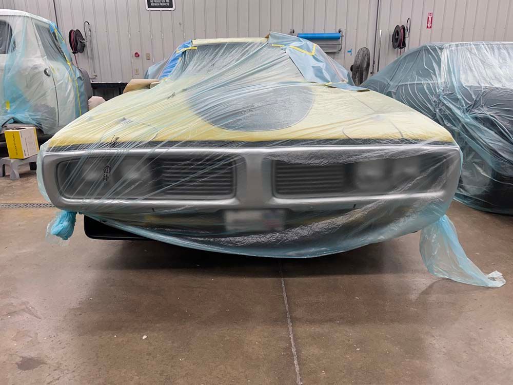 A car is covered in plastic wrap in a garage.