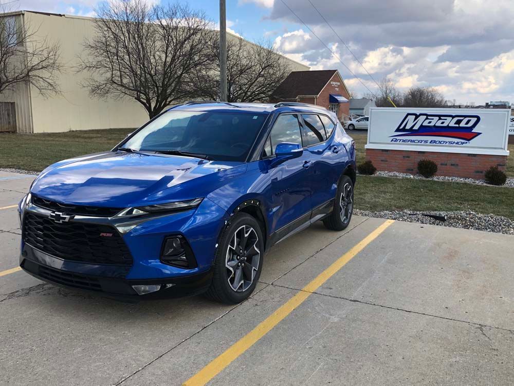 A blue chevrolet blazer is parked in a parking lot in front of a building.