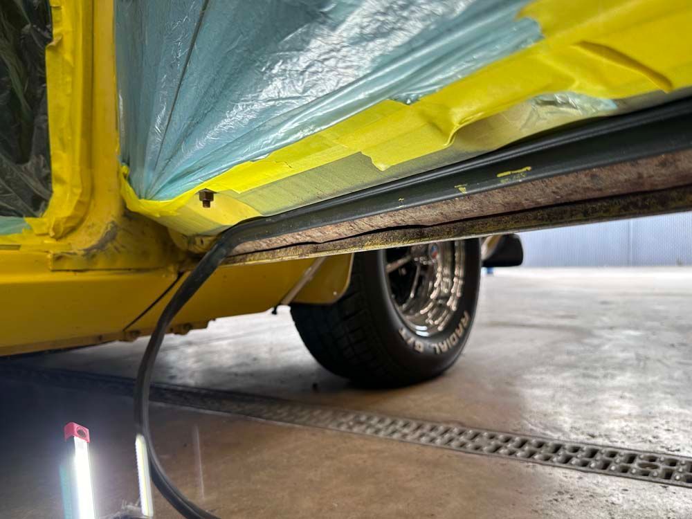 A close up of a yellow car with a hose attached to it