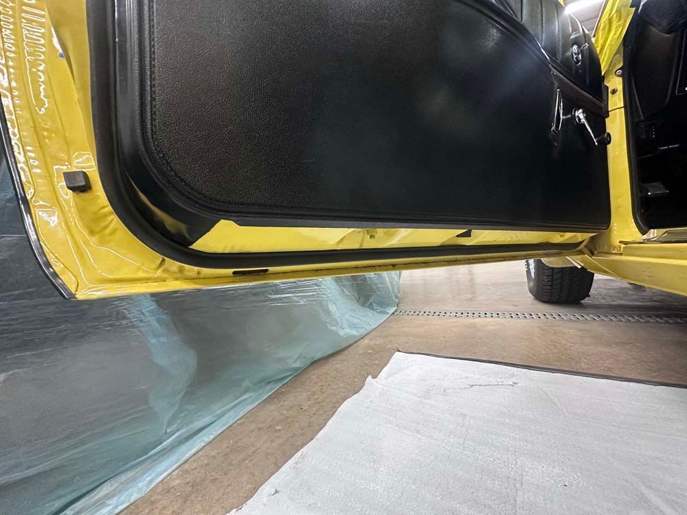 A yellow car is parked in a garage with the door open.