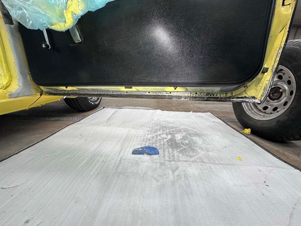 A yellow car is parked next to a black car on a white mat.