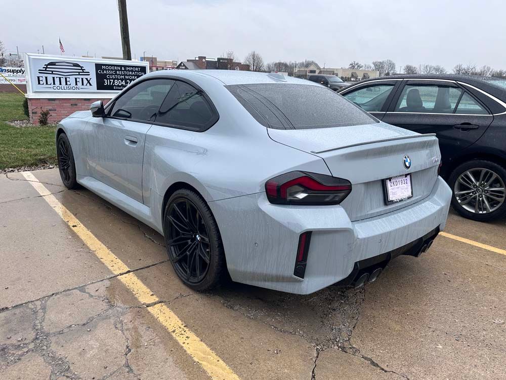 A white bmw is parked in a parking lot next to a black car.