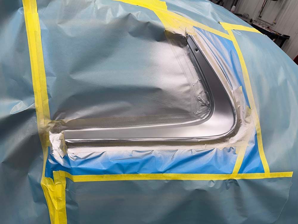 A car is covered in blue plastic and yellow tape