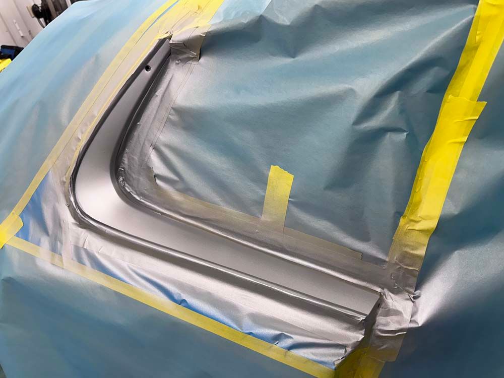 A car is covered in plastic and tape and ready to be painted