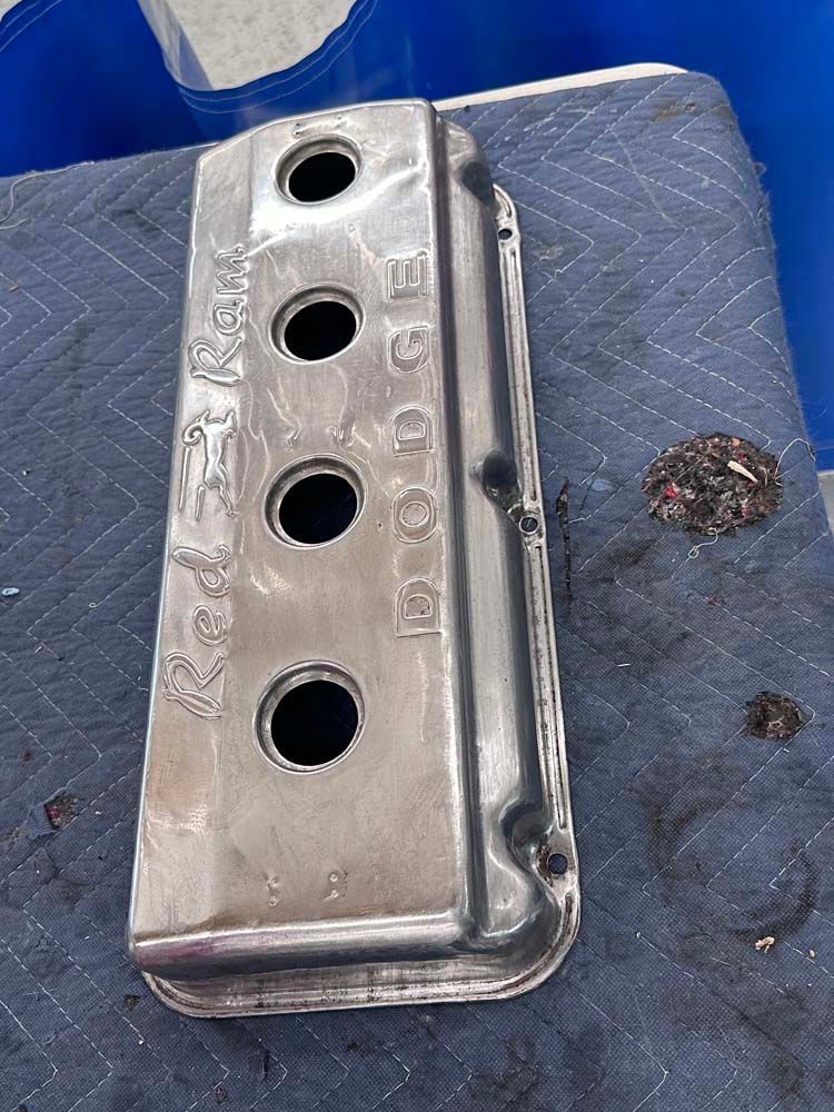 A silver valve cover is sitting on top of a blue table.